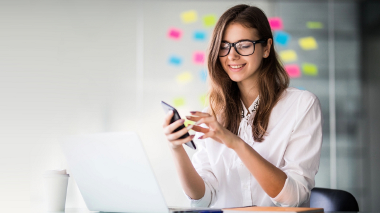 A smiling professional on her smartphone in a modern office environment.