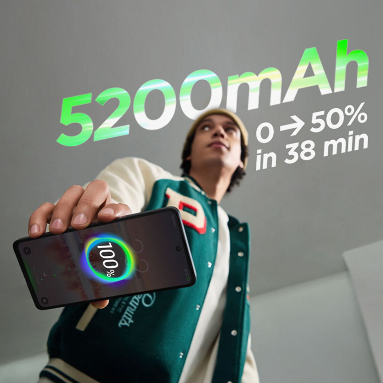 Young man holding a smartphone with a fully charged battery graphic displayed on the screen.