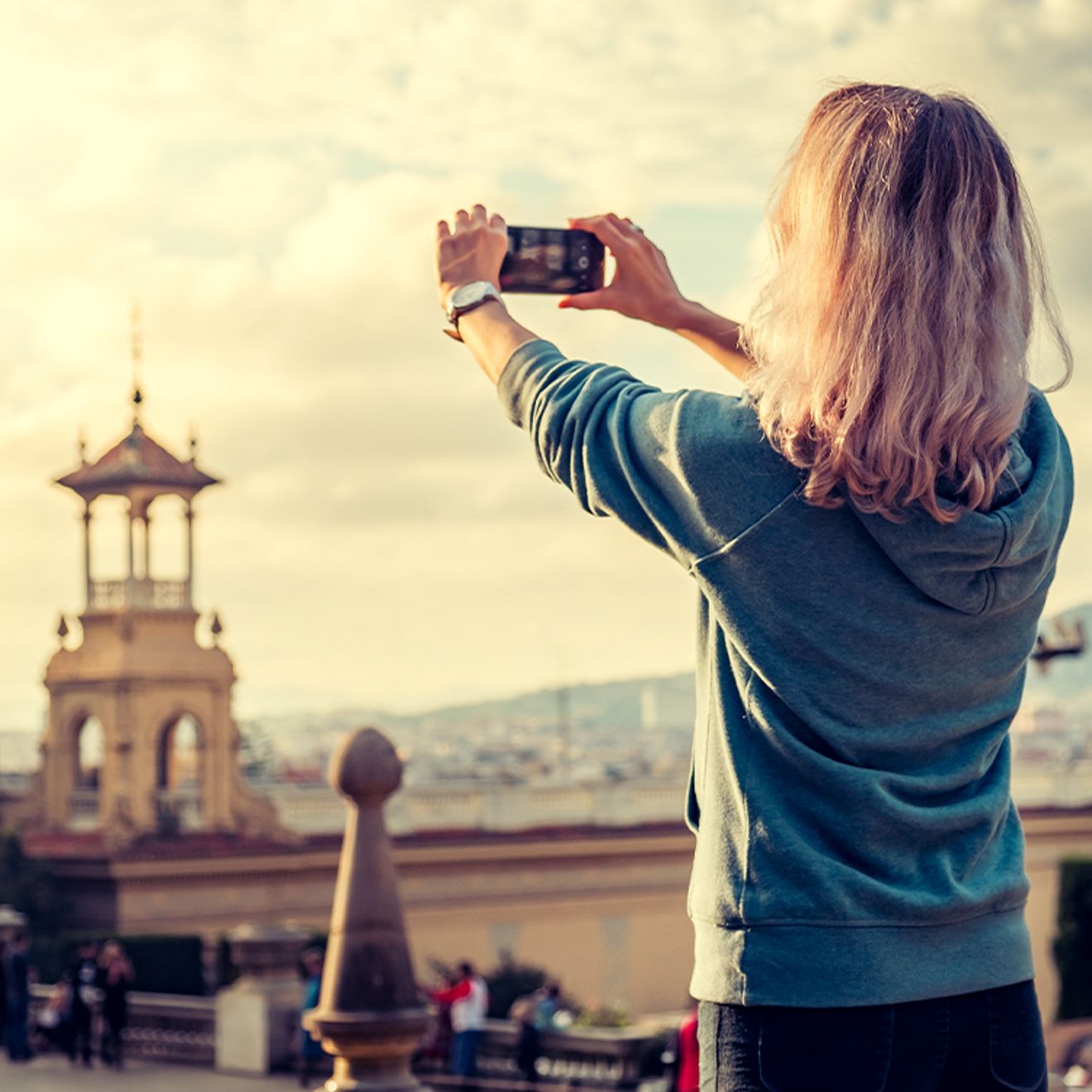 A woman taking a photo of a scenic landmark with a smartphone.