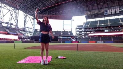 A baseball fan takes a photos of a stadium with her mobile phone.