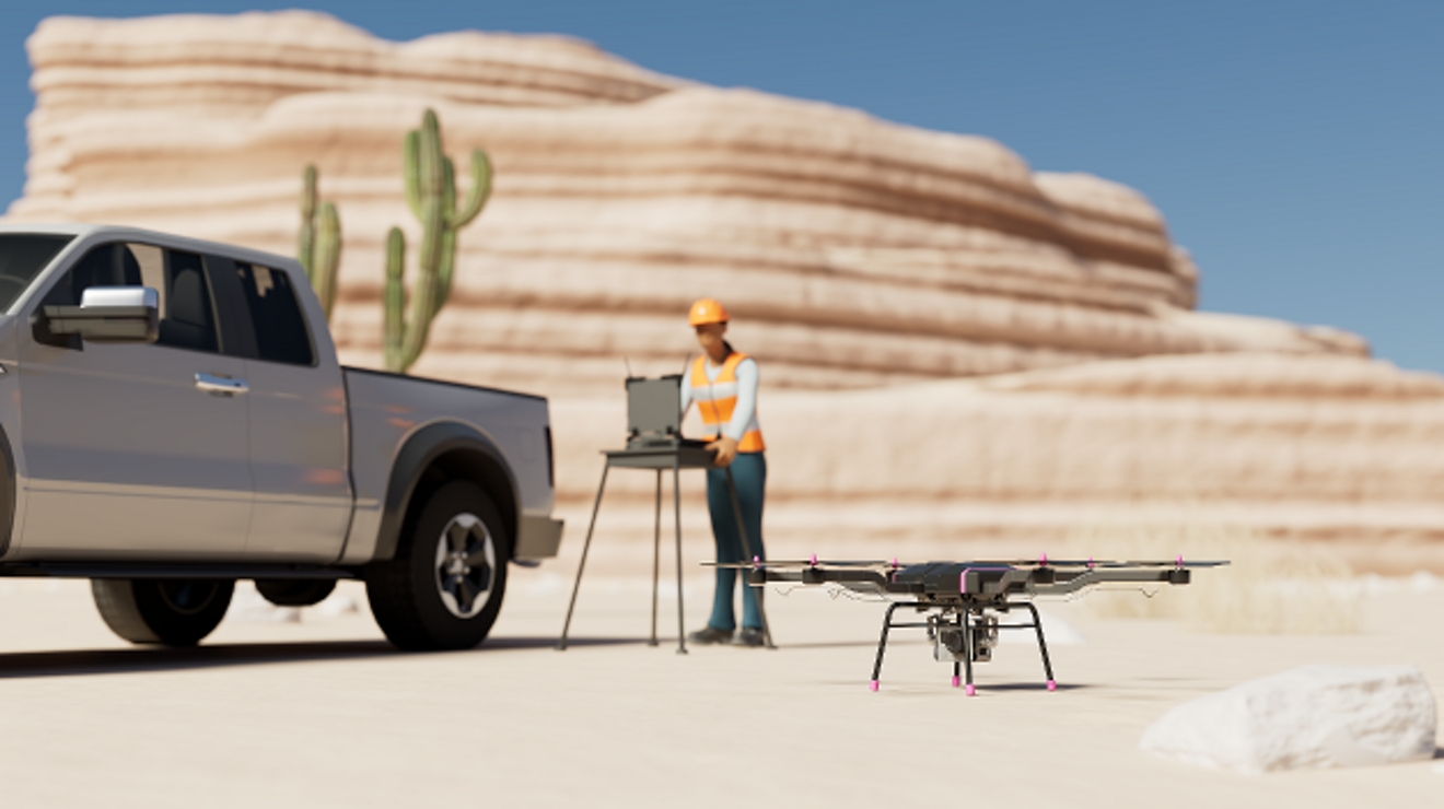 A technician with a laptop prepares to launch a drone in the desert.