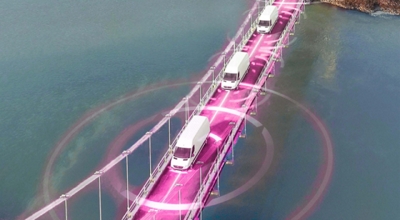 Three connected semi-trucks drive across a bridge.