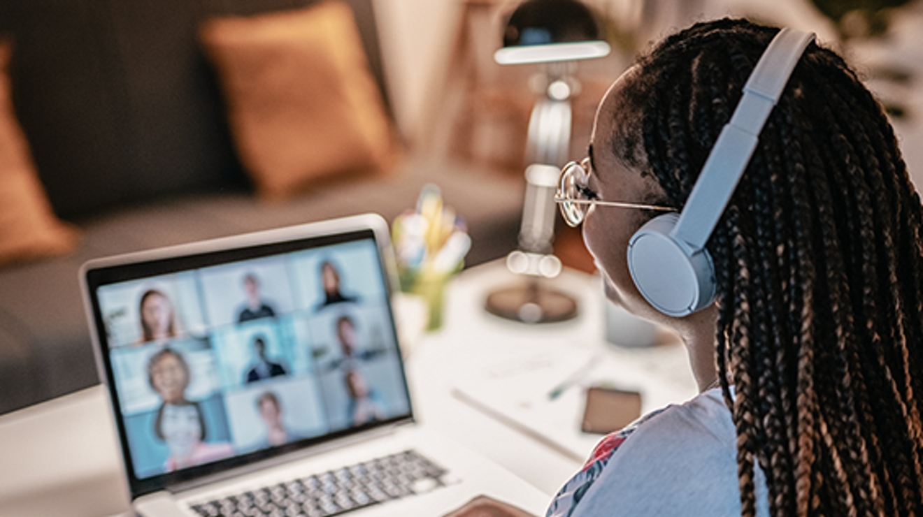 Two female students look at a third smiling student who holds a VR viewer to her head.