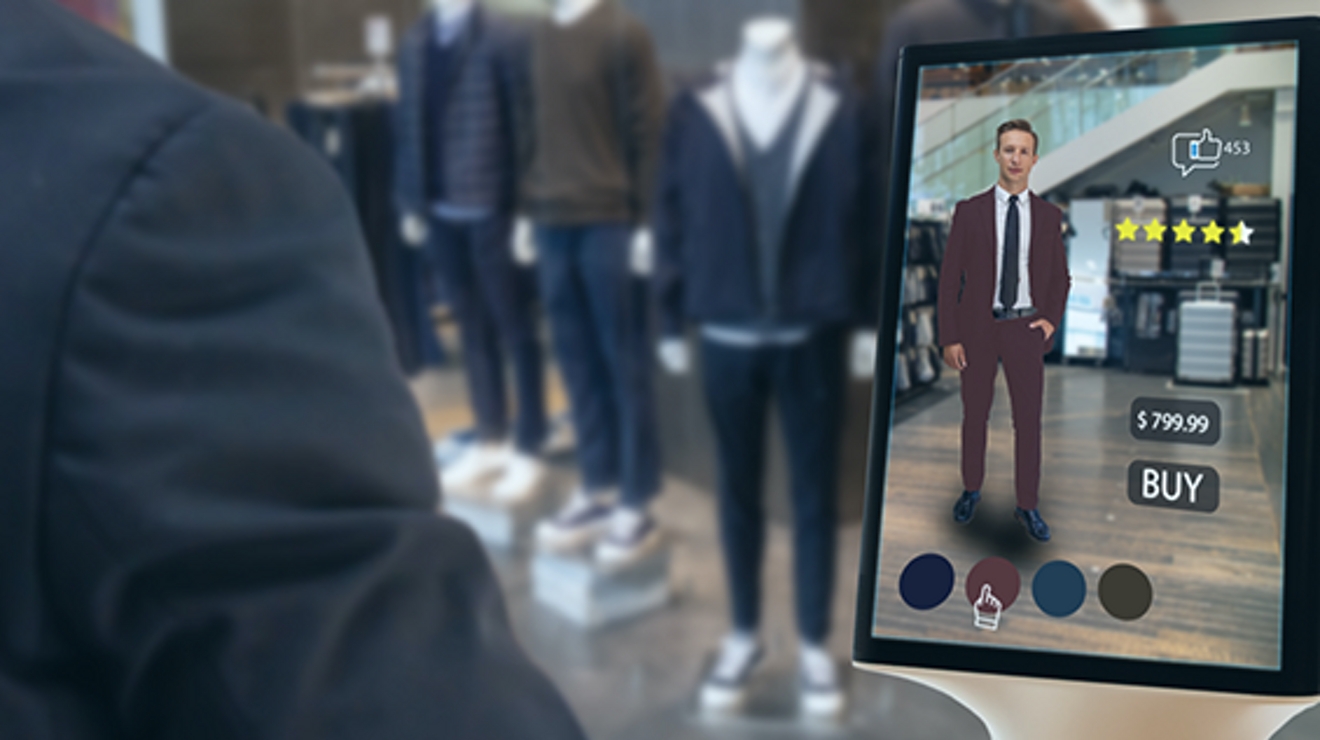 Back of man an in store with mannequins and device in front of him