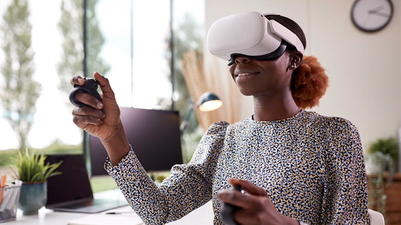 Office worker wearing VR glasses and holding VR tools gestures in the air.