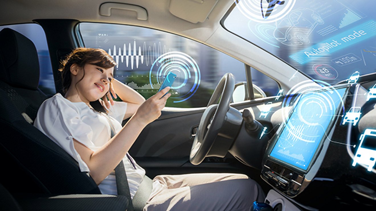 A woman on her smartphone in the driver’s seat of her parked connected car. Graphics represent enhanced features and data. 