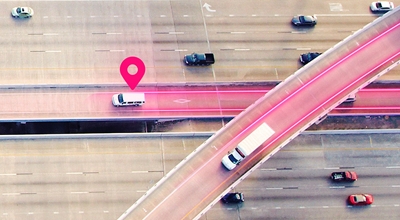 Arial view of white vehicles driving on a freeway lane highlighted in magenta