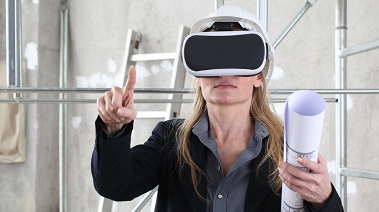 An engineer holding plans and wearing an AR headset on a job site gestures at something in her virtual space.