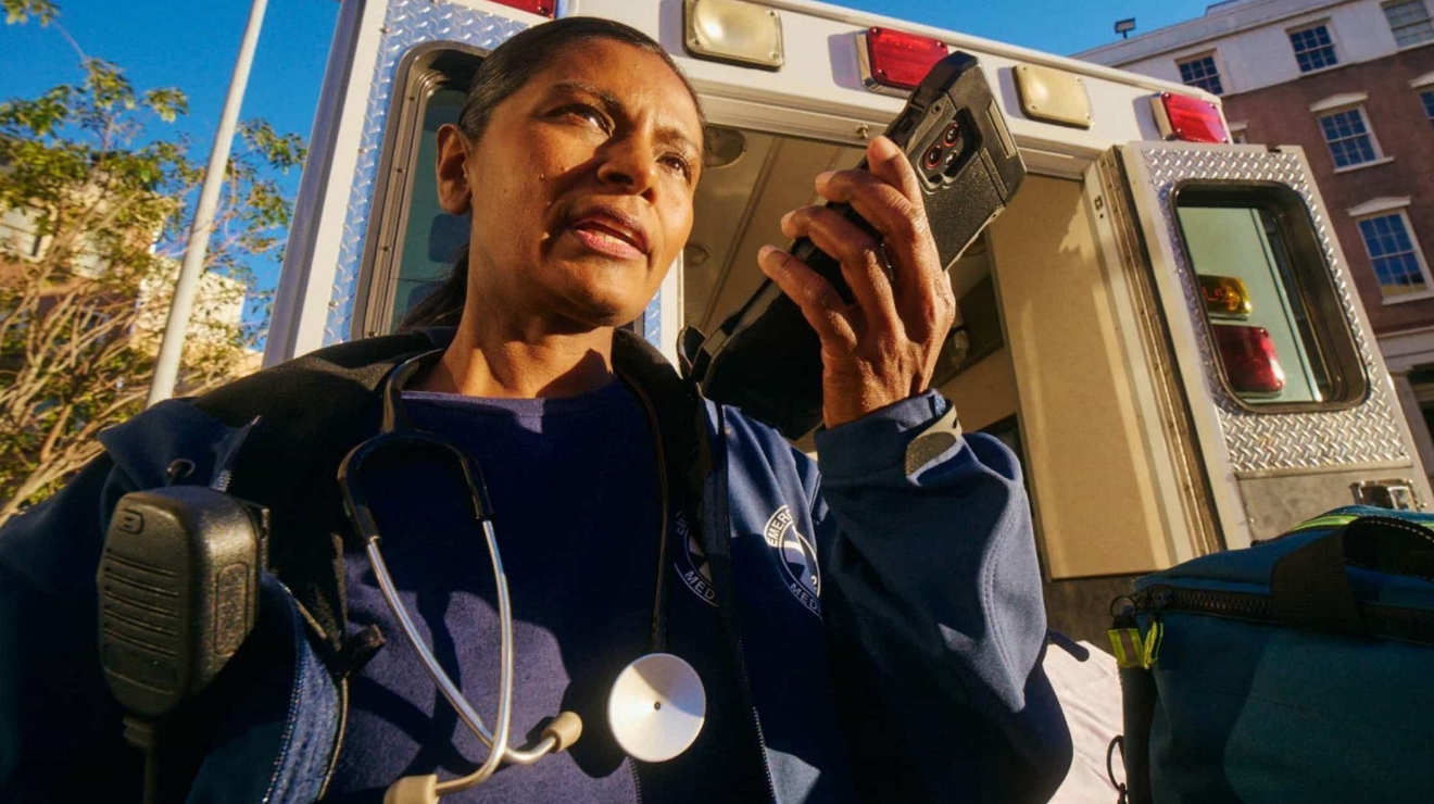An EMT near an ambulance uses a tablet enabled with Direct Connect, a push-to-talk service.