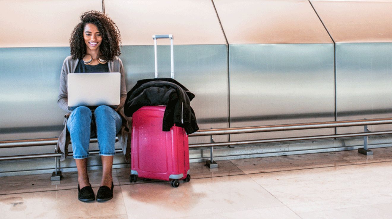 A young professional waits at baggage claim but she can still get work done on her connected laptop.