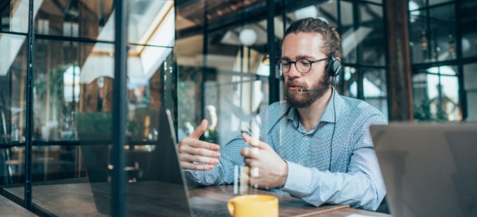 A customer service agent on a call in a coffee shop.