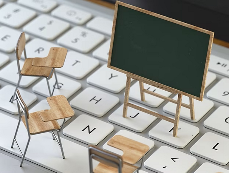 Miniature classroom desks and chalkboard on a laptop keyboard