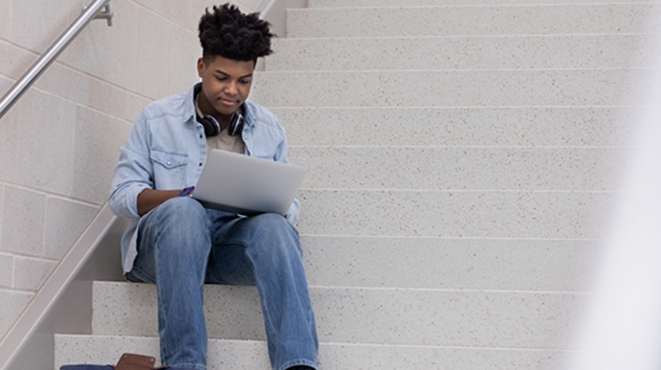 student using a laptop on stairs