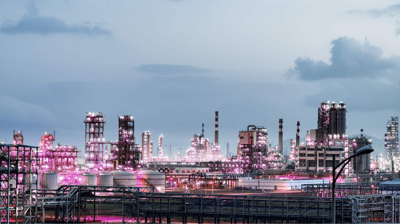 An oil refinery aglow in magenta light.