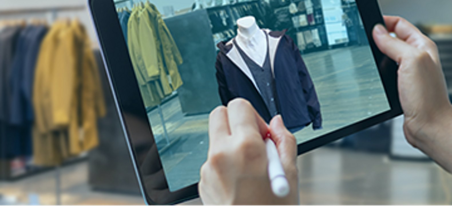 Hand holding pen and tablet with mannequin wearing jacket