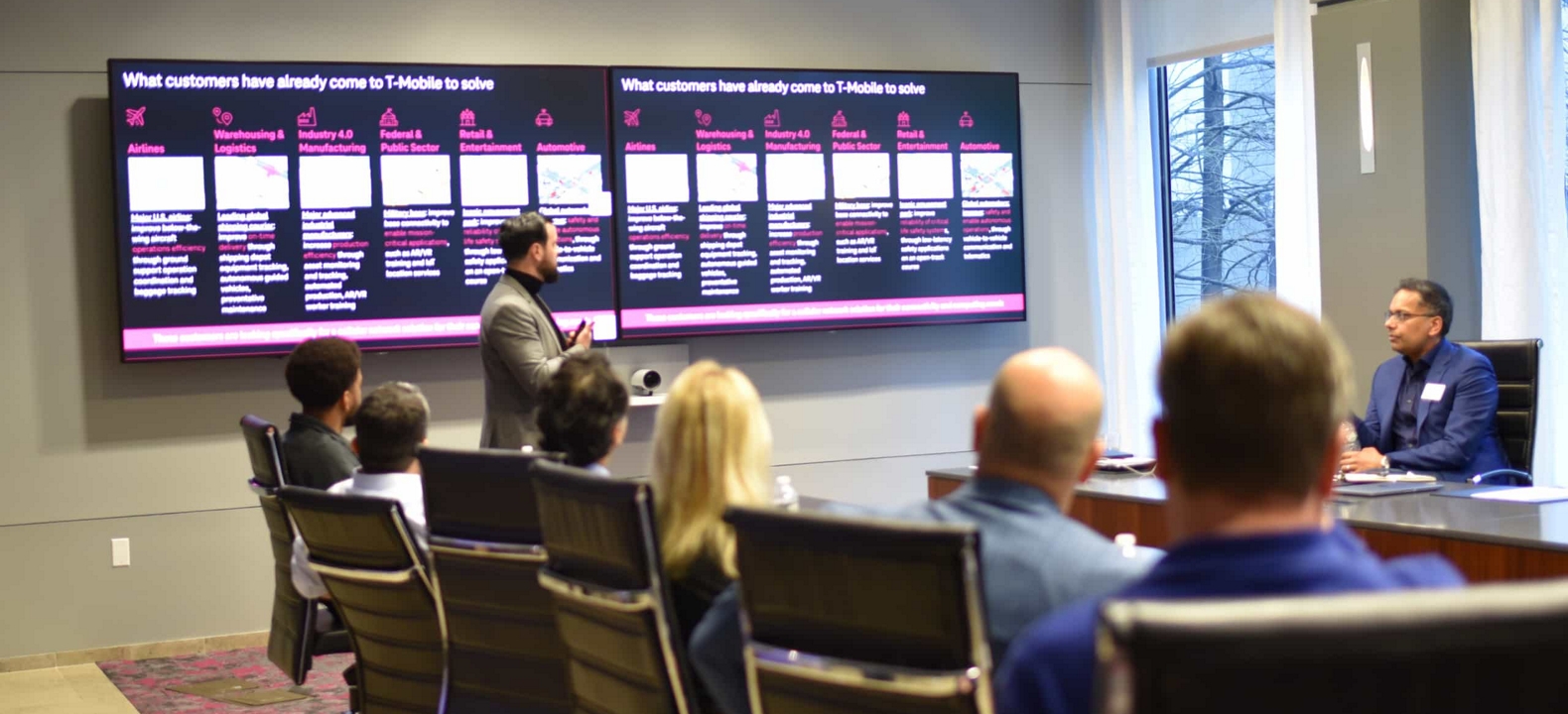 A T-Mobile expert uses two large-format screens to present T-Mobile solutions to an executive group.