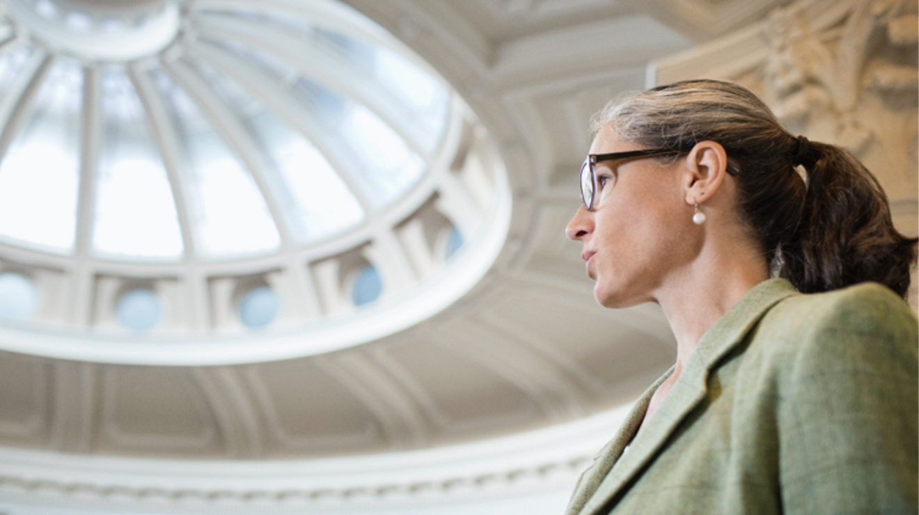 A government employee in conversation, the rotunda ceiling of a government building visible in the background.