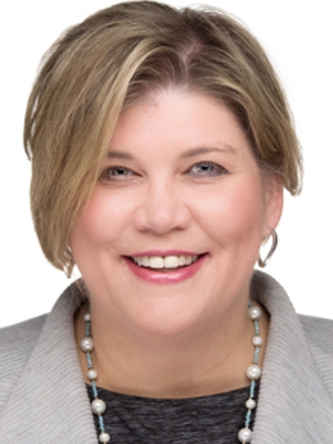 Man with dark sweater, button shirt and ID around neck stands with tablet