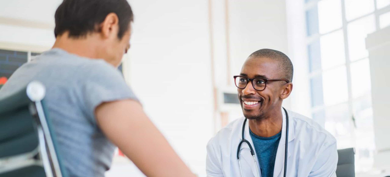 A smiling healthcare professional interacts with a patient in a medical office.