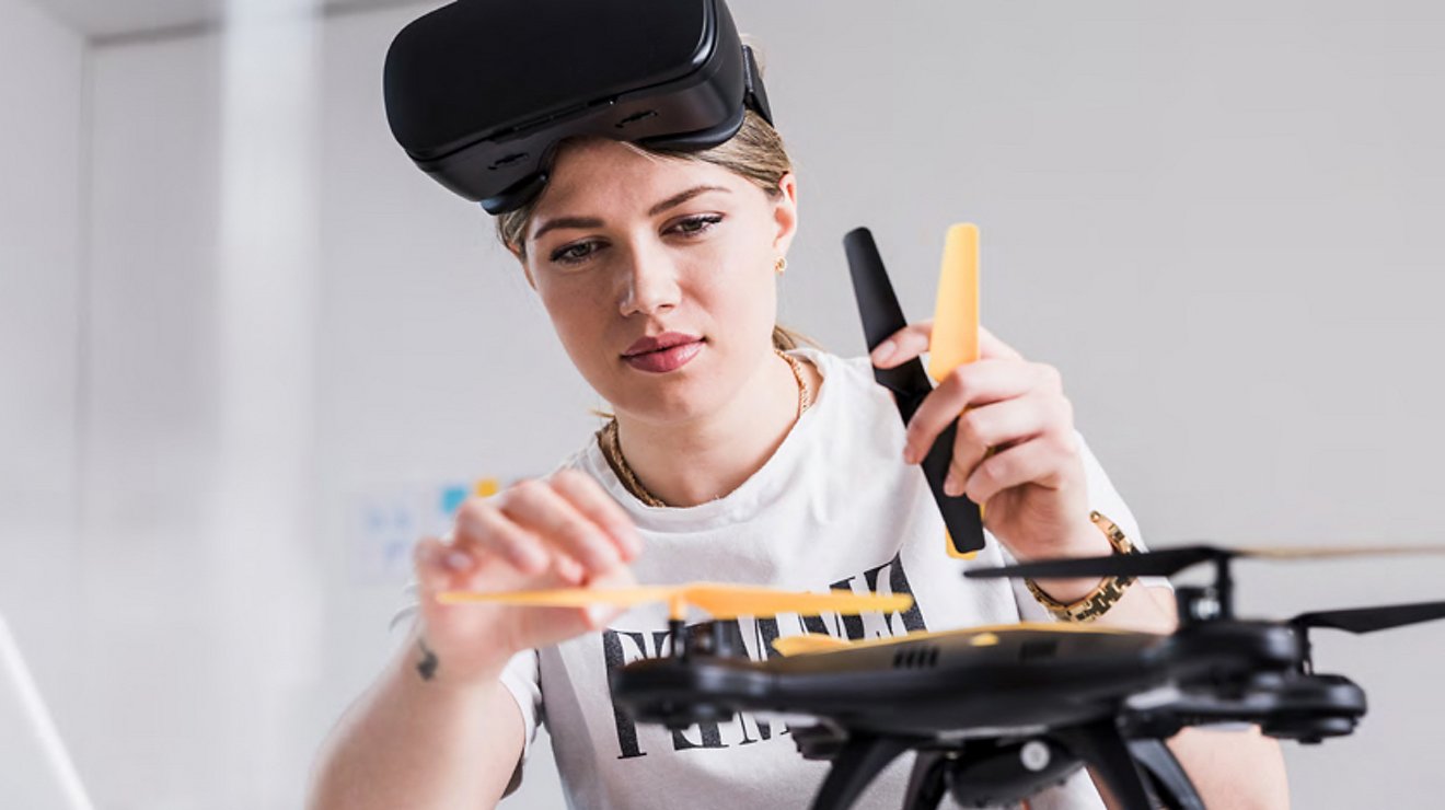 Woman with goggles on forehead working on a drone
