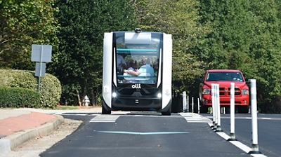 Two people embrace while riding down the street in a futuristic looking vehicle.