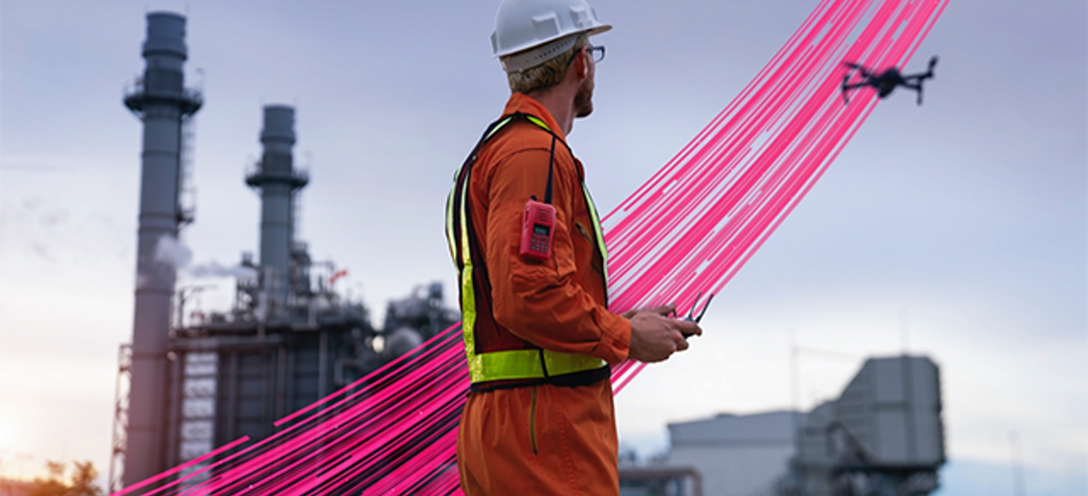 A worker flies a drone at an industrial site, across magenta beams that suggest connections from sky to ground.