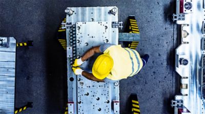 Construction man wearing yellow hard hat working on machine