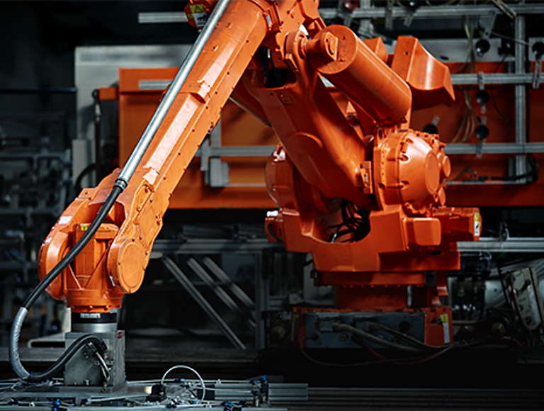 Large orange robotic arm inside of a factory.