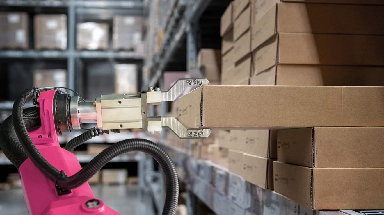 A robotic arm grips a rectangular cardboard box on a warehouse shelf.