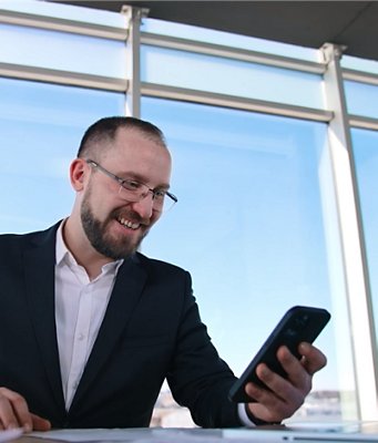 A smiling professional checks his smartphone.