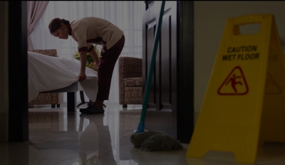 Housekeeper making a bed in a hotel room