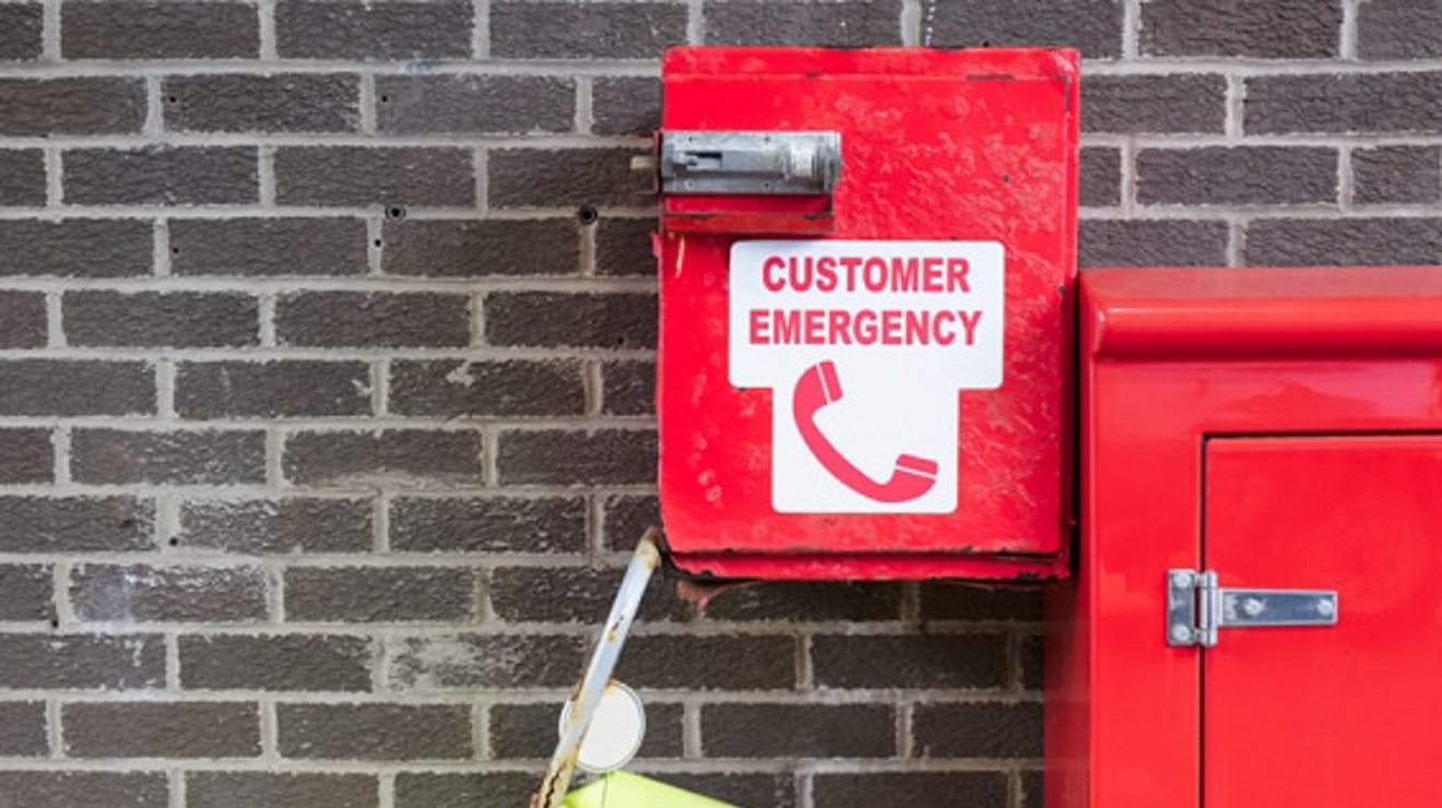 A customer emergency phone box and emergency kit on a brick wall.