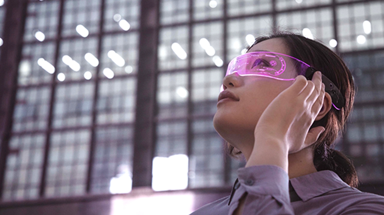 Woman in VR-augmented glasses stands in front of an office building
