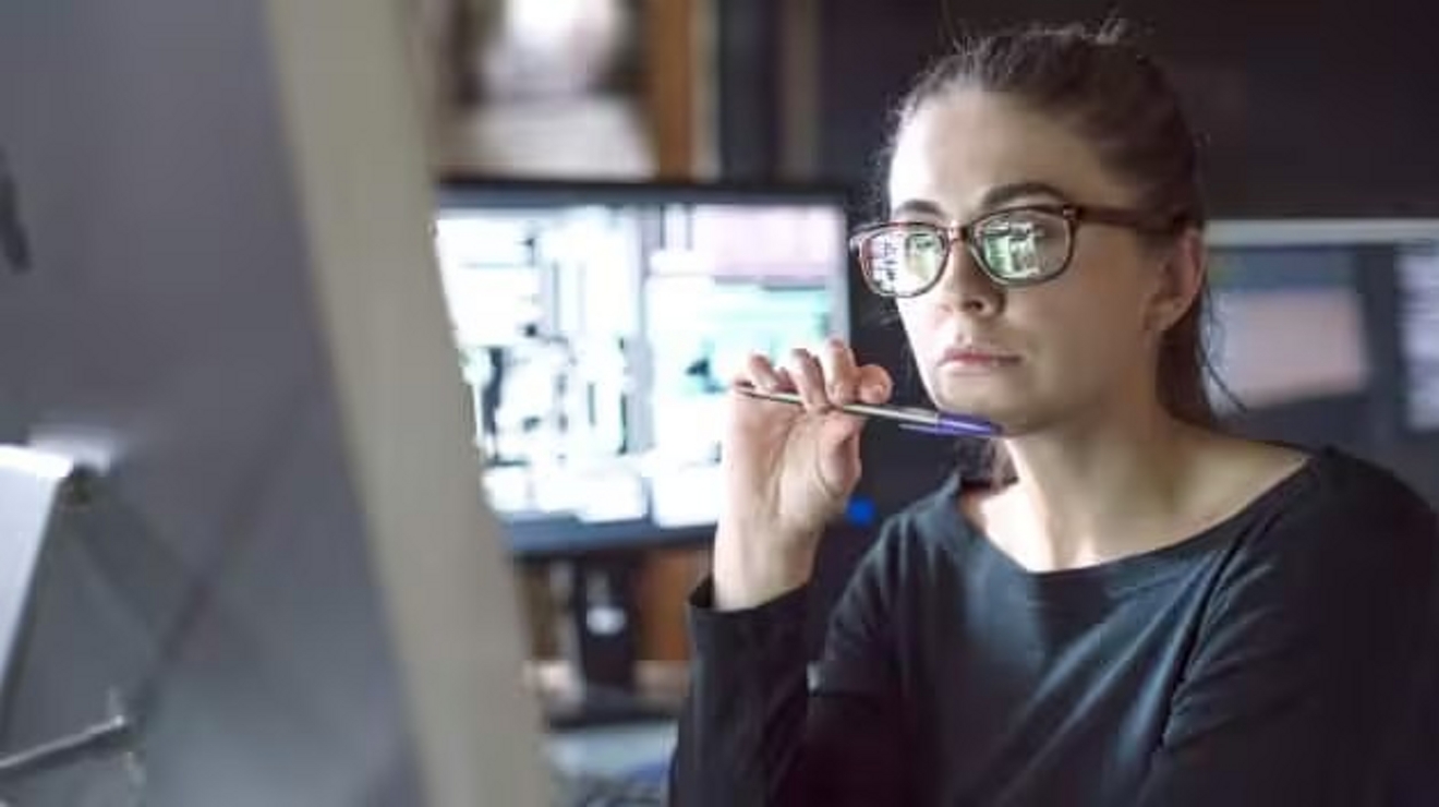 The images of a computer screen are reflected on a professional’s eyeglasses. 