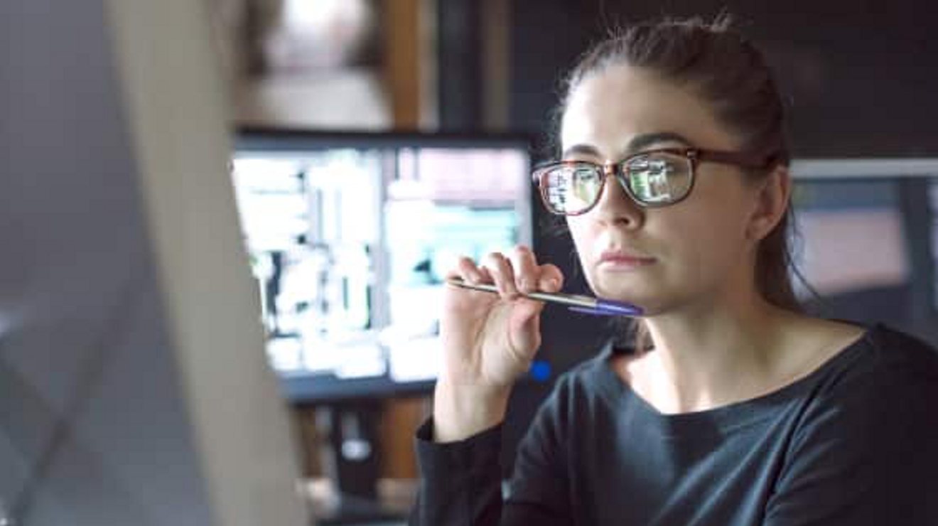 The images of a computer screen are reflected on a professional’s eyeglasses.