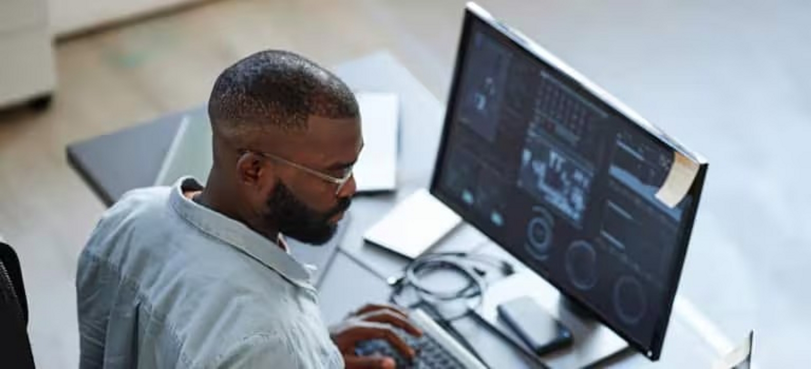 Overhead view of a professional working with a laptop and a desktop screen.