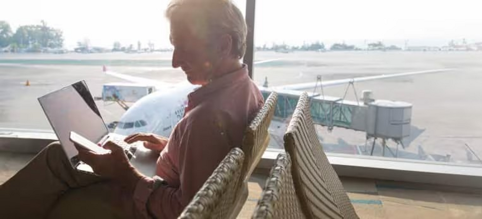 A professional works with a computer and a cellphone in an airport gate.