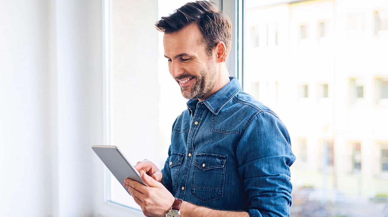 A business executive in a building lobby holds their smartphone as they press an elevator button