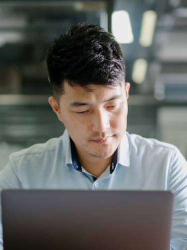 A professional works on his laptop computer in an open workspace.