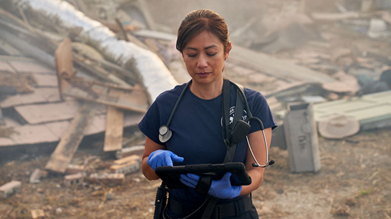 An emergency medical responder uses her tablet at a disaster site.