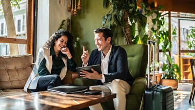 Two travelers in a café stay in touch with home on their connected tablet.