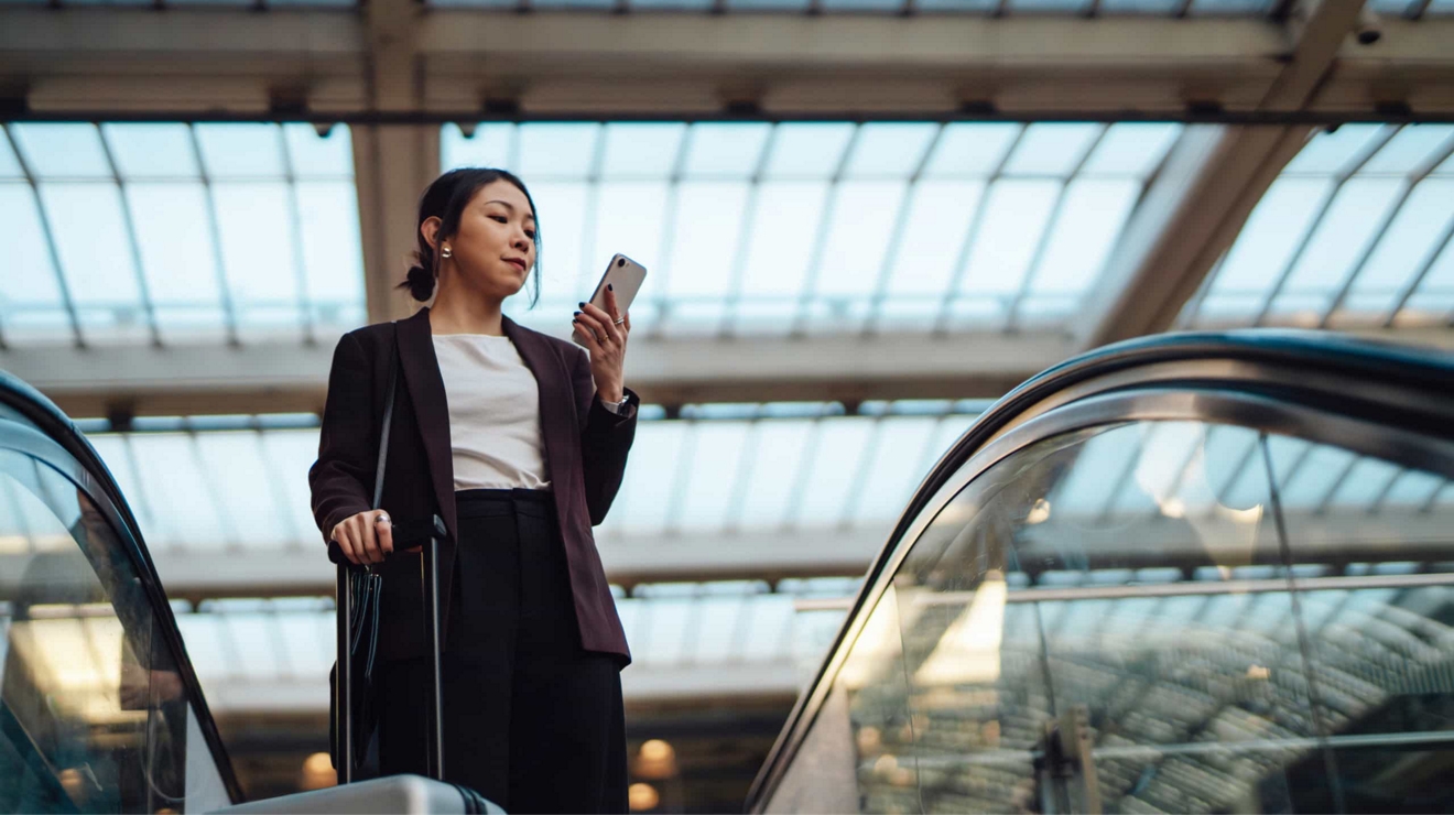 A business traveler checks her smartphone in an airport terminal.