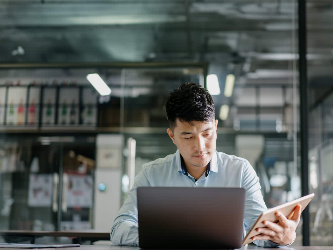 A business professional securely works on their laptop and tablet at a desk.