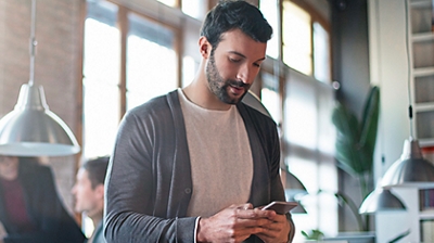 A professional uses his smartphone in a casual office setting.