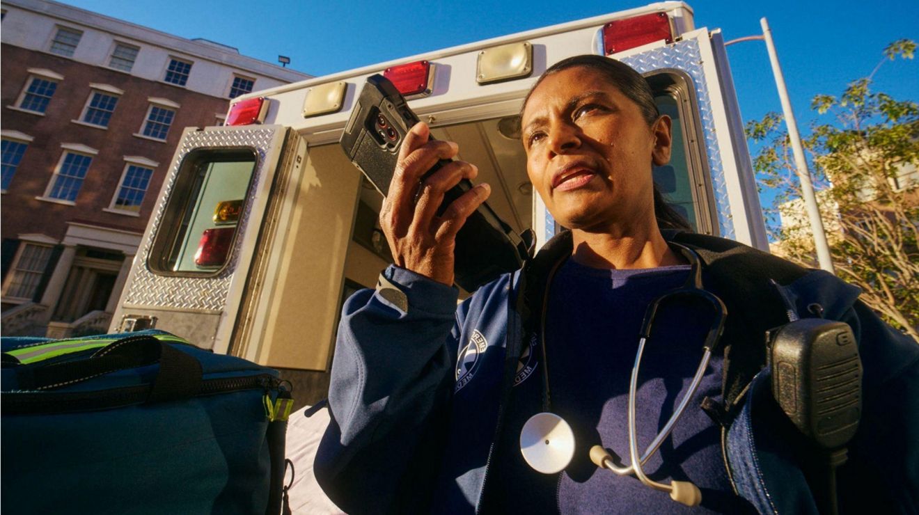 An EMT near an ambulance uses a device enabled with Direct Connect, a push-to-talk service.   