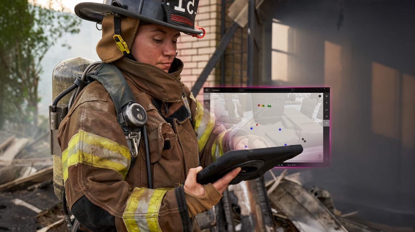 A firefighter in full gear uses a tablet to locate fire crews in a block of downtown buildings.