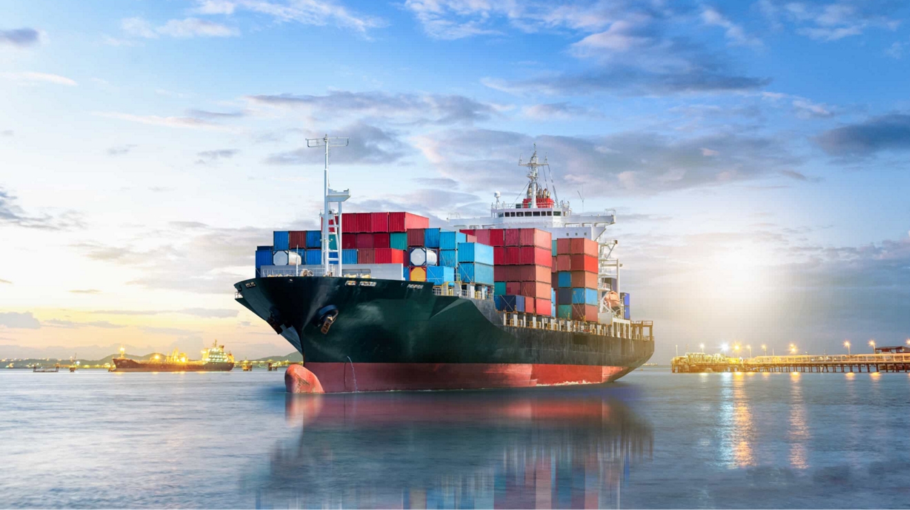A container ship at anchor in a modern shipping port.