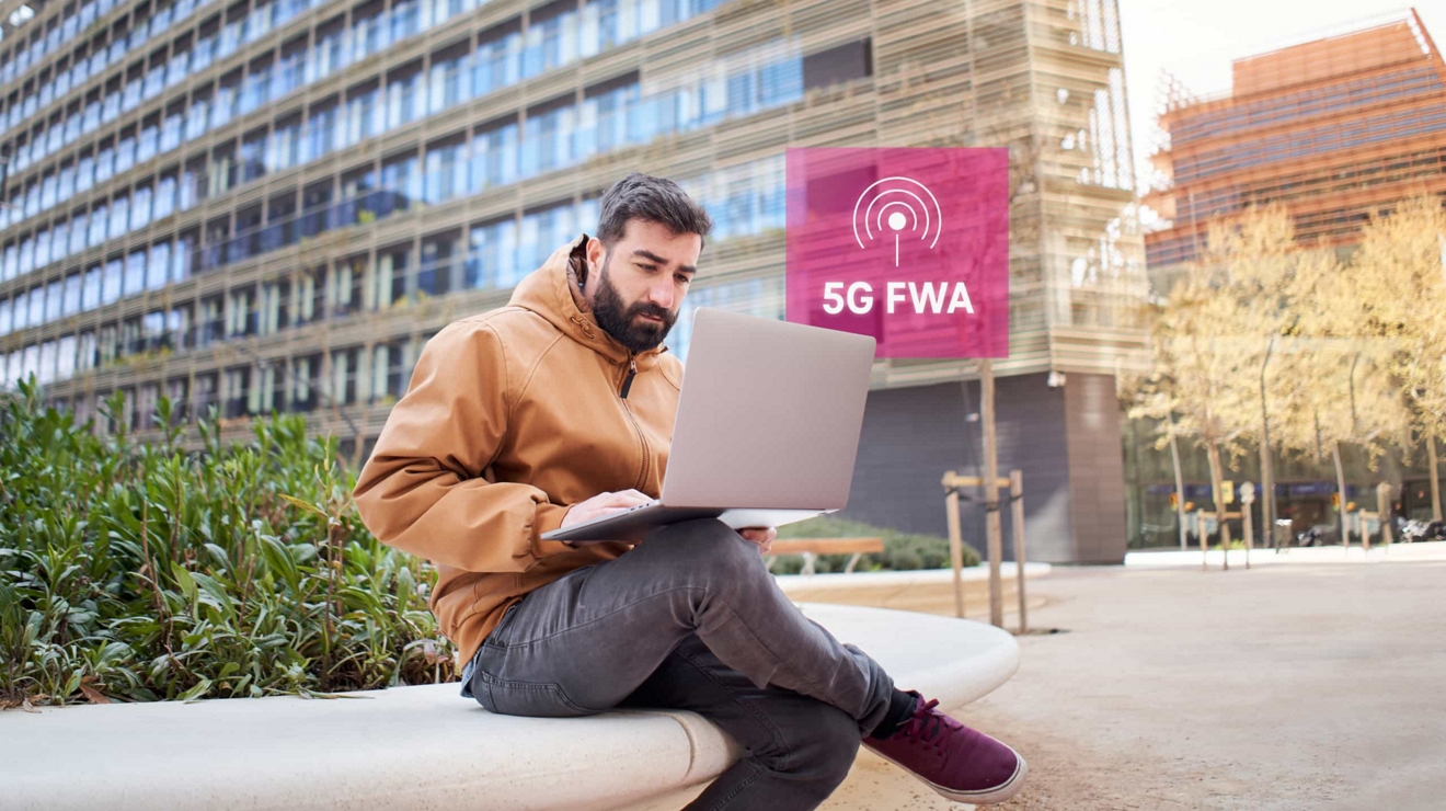An employee works on their laptop outside a downtown office using 5G fixed wireless access.