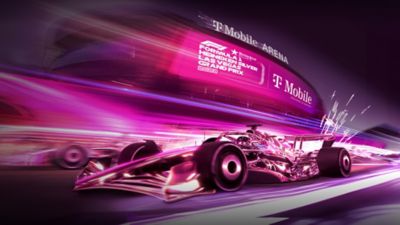 A magenta Formula 1 car racing on a magenta track outside the T-Mobile Arena.