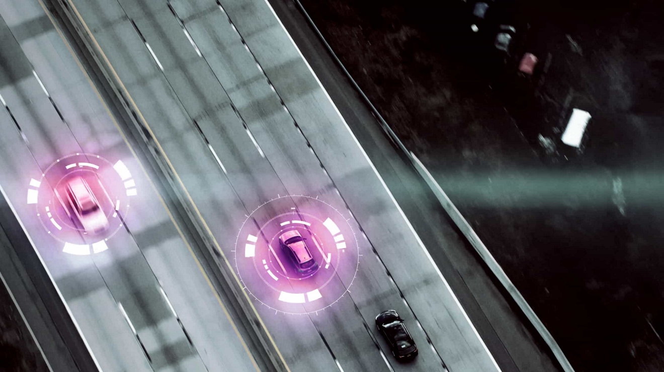 Two vehicles driving on the highway, each radiating circular magenta connectivity bands.
